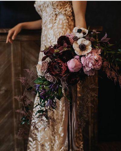 Bridal bouquet, bride’s bouquet with flowers done by Sweet Elegance Floral design florist in Kelowna, BC. Hand tied dark, moody bouquet with anemones, roses, peonies in pink, purple and cream with flowing purple ribbons.